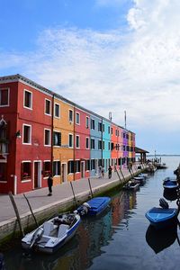 Boats moored by building in city against sky