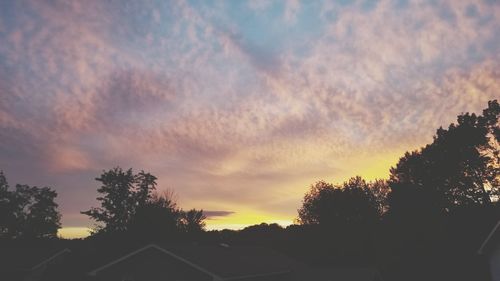 Low angle view of silhouette trees and building against sky during sunset