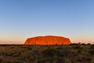 Rock formations on landscape against clear sky during sunset