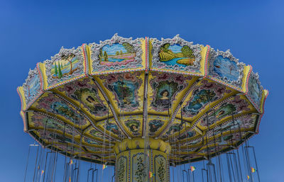 Low angle view of amusement park against blue sky