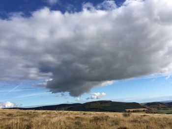 Scenic view of grassy landscape against cloudy sky