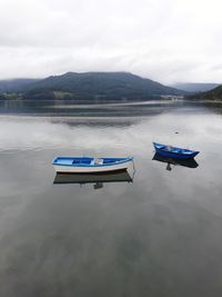 Boat moored on lake against sky