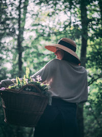 Midsection of person wearing hat in basket against trees