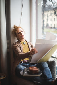 Woman holding mobile phone while sitting at home