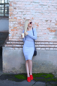 Full length of woman standing against wall