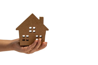 Close-up of hand holding small house against white background