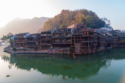 Buildings by lake against sky