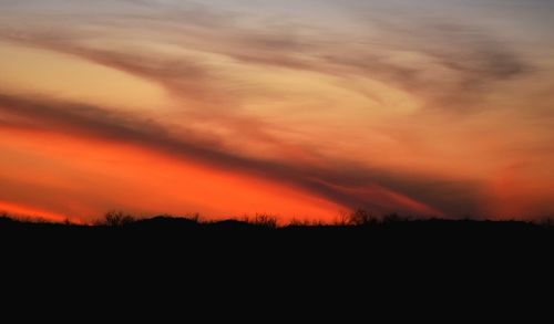 Scenic view of silhouette landscape against orange sky