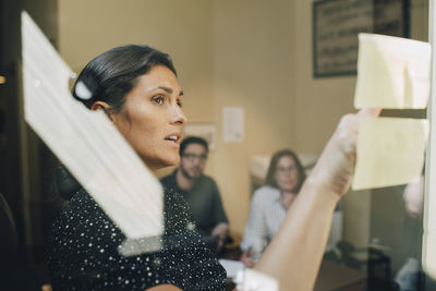 Mid adult businesswoman sharing ideas to colleagues in board room