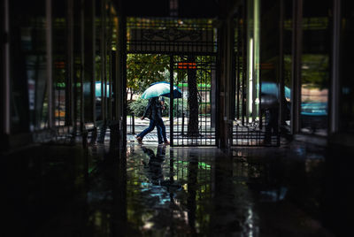 People walking with umbrella during monsoon seen from doorway