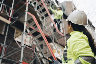 Female building contractor wearing hardhat examining construction site