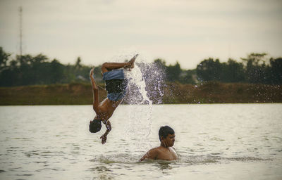 Full length of shirtless man splashing water in lake