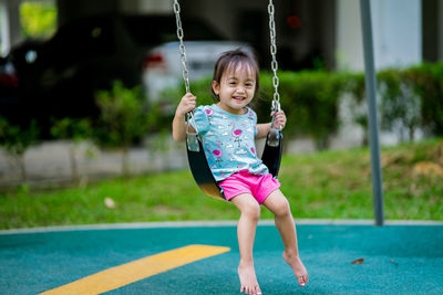 Portrait of smiling girl playing on swing