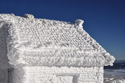 Cropped snowed built structure against blue sky