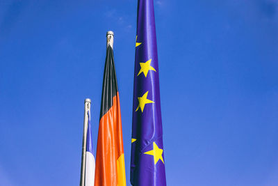 Low angle view of flags against clear blue sky during sunny day