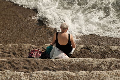 Rear view of woman sitting on beach