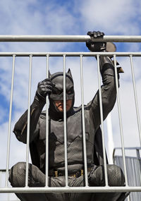 Man sitting on metal railing against sky