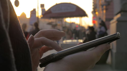 Midsection of man holding mobile phone in city