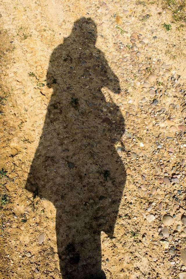 HIGH ANGLE VIEW OF MAN SHADOW ON SAND