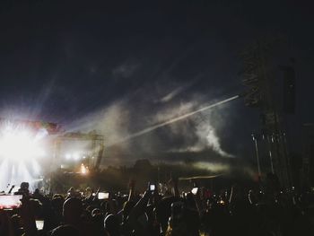 Crowd at music concert against sky at night