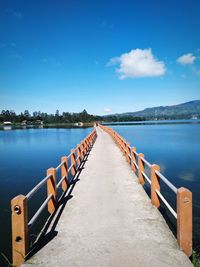 Empty pier over lake against blue sky