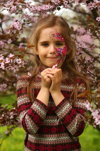 Spring portrait of a six year old girl standing under the blooming pink cherry tree