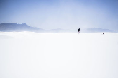 Women standing on snow covered landscape against clear sky