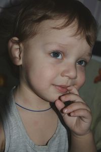 Close-up of cute baby boy with finger on lips looking away