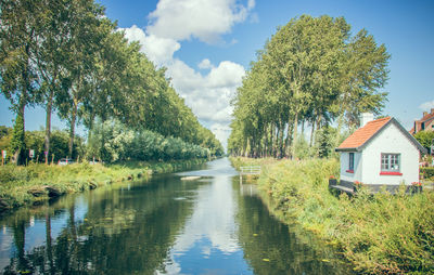 Scenic view of river amidst trees and houses against sky