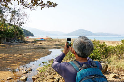 Rear view of man taking picture from phone