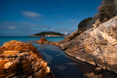 Rock formations on beach against sky