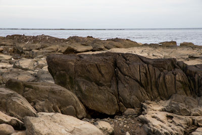 Scenic view of rocks on beach against sky