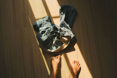 Low section of men standing by jeans on hardwood floor