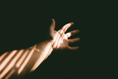 Cropped hand of man against black background