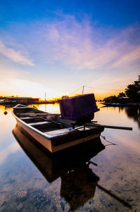 Boat moored on sea against sky during sunset