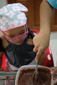 Close-up of hand helping girl preparing food on table