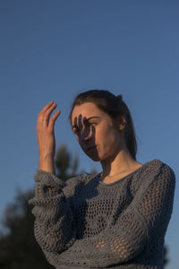 Young woman looking at camera against blue sky