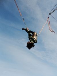 Low angle view of boy enjoying chain swing ride against sky