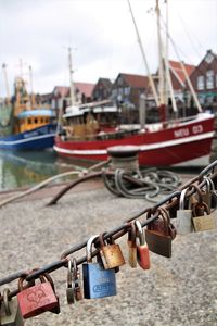 Padlocks on railing by river in city against sky