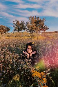 Woman sitting amidst plants on land against sky