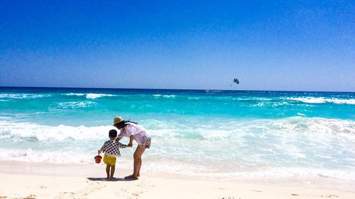 Mother with child at beach against sky