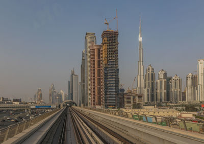 Railroad tracks amidst buildings in city against clear sky