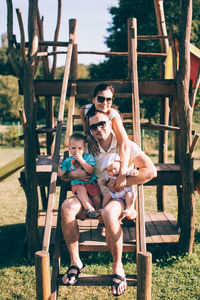 Portrait of friends sitting on slide at playground