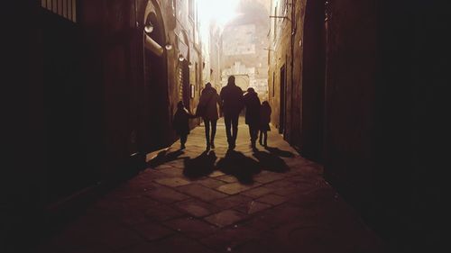Silhouette people walking in alley