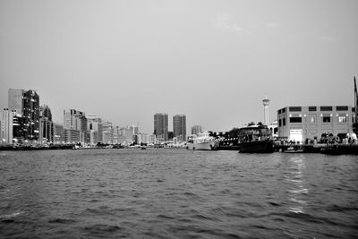 Sea by buildings against sky in city