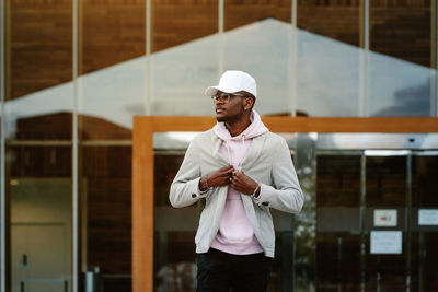 Young man wearing hat standing against wall