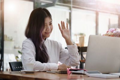 Woman using phone while sitting on table