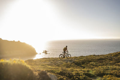 Mature sportsman riding electric mountain bike on cliff