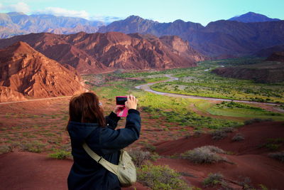 Rear view of woman photographing on mountain