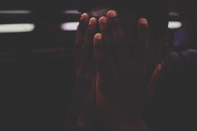 Close-up of man covering face in darkroom